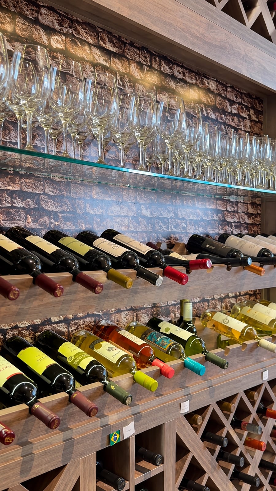 Adega do Grill Hall com taças na prateleira e uma seleção de vinhos