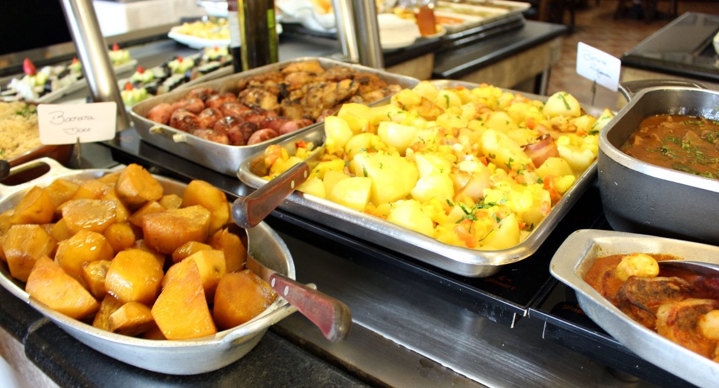 Balcão do buffet quente com travessas de acompanhamentos