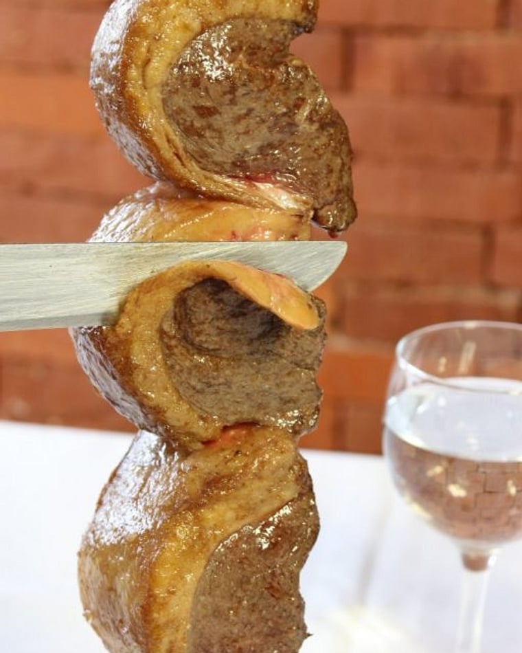 Espeto de carne sendo fatiado no rodízio