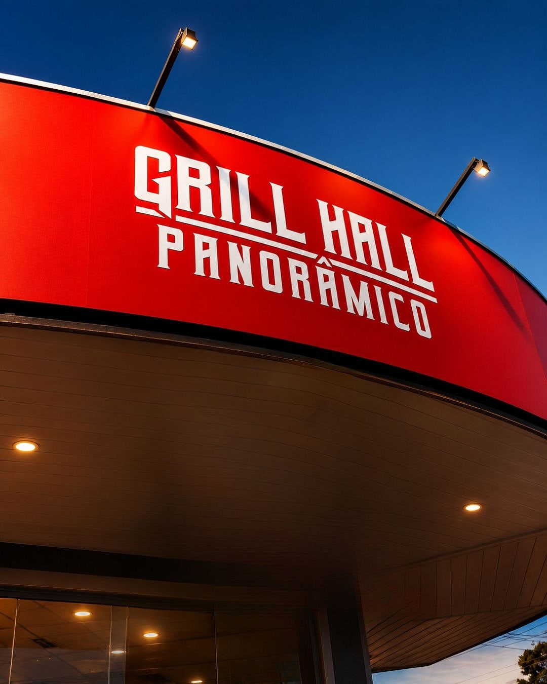 Letreiro do Grill Hall Panorâmico iluminado ao entardecer, com o céu azul ao fundo